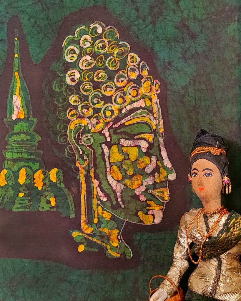 Nancy V Ridenour • <em>Buddha Batik and Lao Doll</em> • Digital image on canvas • 16″×20″ • $150.00