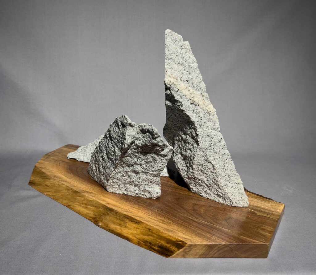 Eva M. Capobianco • <em>Granite Trio</em> • Curb pieces on walnut slab • 19″× 11″× 11″ • $475.00