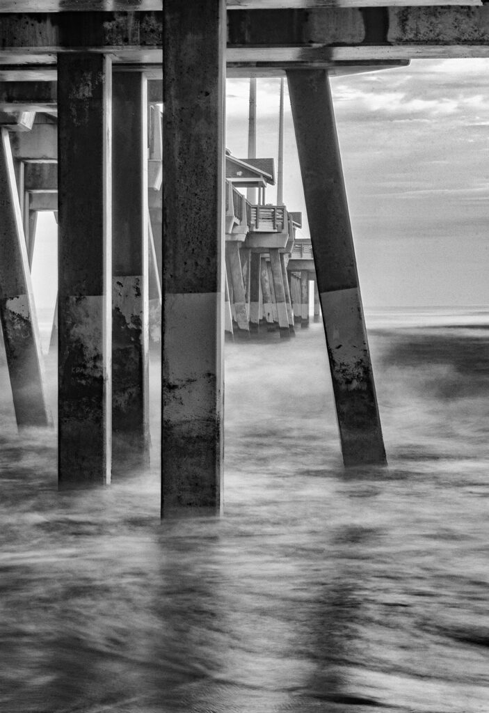 Debra Rockefeller • <em>From Under the Pier</em> • Digital photography BW matte finish metal frame black • 19″× 25″ • $500.00