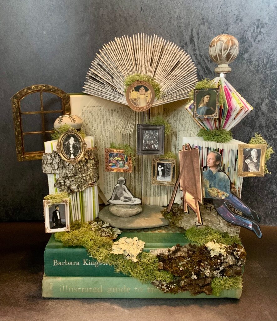 Teresa Yatsko&nbsp;• <em>Artist's Dream</em>&nbsp;• Upcycled books, hand cut paper images, lichen&nbsp;• 13″×&nbsp;14″×&nbsp;7″&nbsp;• $225.00<a class="purchase" href="https://state-of-the-art-gallery.square.site/product/teresa-yatsko-artist-s-dream/OGN36RPS2LHCPQRPMRUJBCPL" target="_blank">Buy</a>